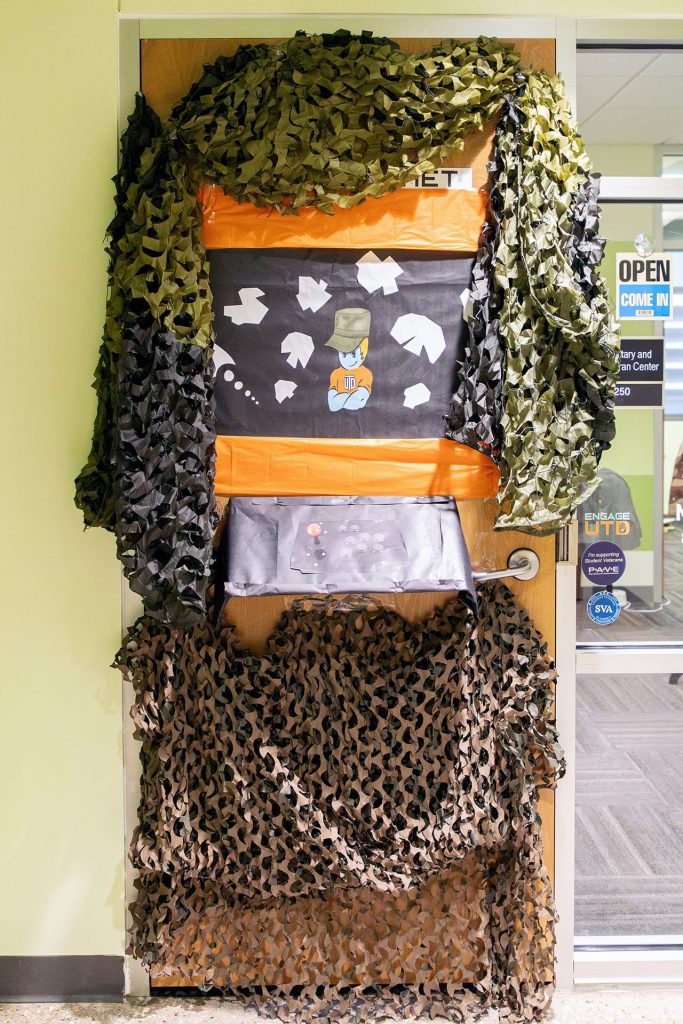 Homecoming Door Decoration: Asteriods! game cabinet draped with military camouflage netting. -SSA 14.250F