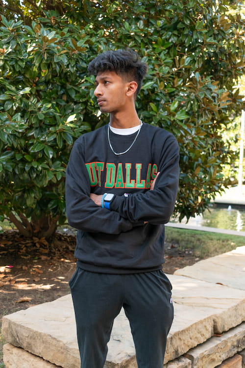 Standing male with arms crossed, modeling a sweatshirt with UT Dallas lettering.