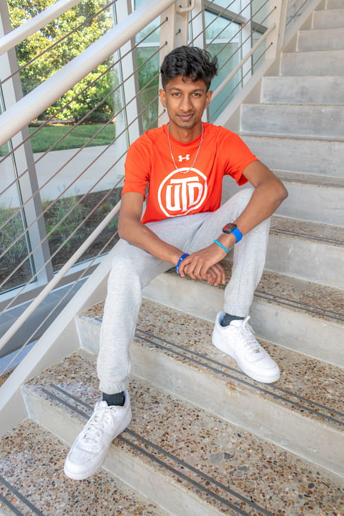 Seated male on staircase, modeling UT Dallas branded apparel.